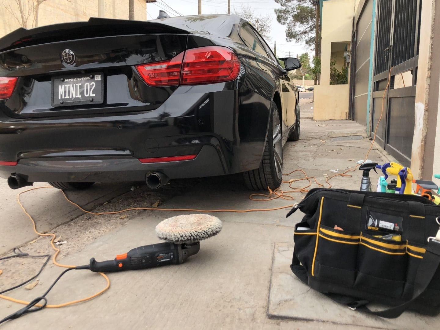 Pulidora junto a un BMW negro después del detallado