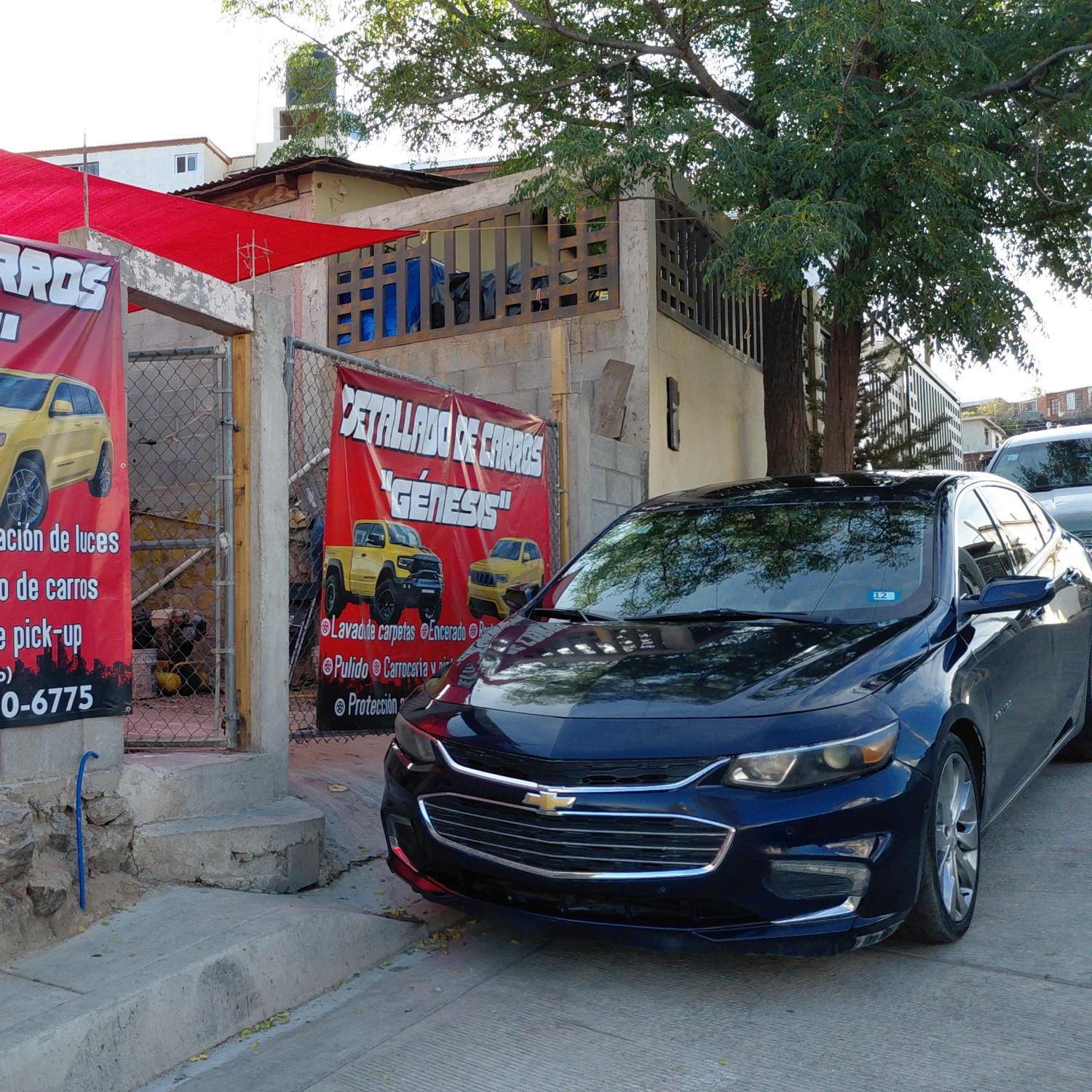 Chevrolet Malibu azul frente a la lona del taller